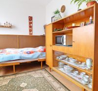 A room in a family house with a bed, retro furniture, and shelves with porcelain.