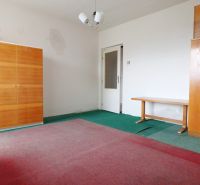 An empty room in a family house with furniture and a green carpet.