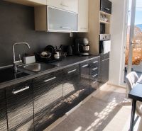 A kitchen in a 2-room apartment with dark cabinets and a wood-patterned floor.