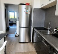 A kitchen in a 2-room apartment with a refrigerator and a floor with a wooden decor.