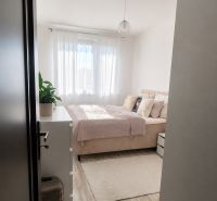 A bright bedroom with a bed and wood-patterned flooring in a 2-room apartment.