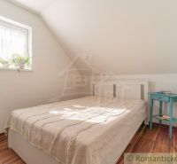 Bedroom in a family house with a bed, nightstand, and floor with wooden decor.