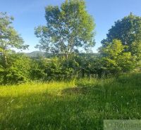 Gardens in Podkylava with a lawn, trees, and a view of nature under a blue sky.