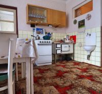 A kitchen in a family house with a carpet, dining table, and gas stove.