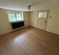 A room in a family house has a wooden decor floor and white walls.