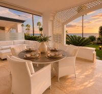 Terrace of a 4-bedroom apartment with an ocean view, comfortable seating, and elegant dining.