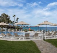 A pool with loungers and palm trees by the beach at Dominion Beach in Estepona.