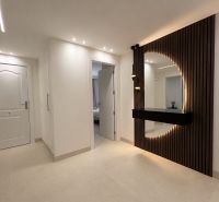 A hallway in a 4-room apartment, elegant furniture with lighting and design elements on the wall.