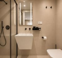 Bathroom with a shower, mirror, and wall-mounted sink in a 4-room apartment.