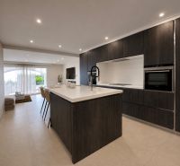 A kitchen in a 4-room apartment with dark cabinets and an open space to the living room.