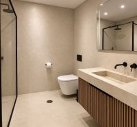 A bathroom in a 4-room apartment with a shower and wooden decor on the cabinet.