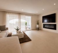 Living room of a 4-room apartment with a comfortable sofa and a TV on the wall.