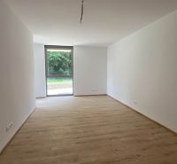 A spacious room in a recreational apartment with white walls and a wood-patterned floor.