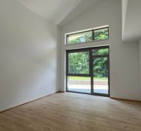 Interior of a holiday apartment with a large window and wooden decor flooring.