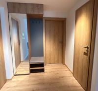Interior of a holiday apartment with a wooden decor floor and a built-in wardrobe with a large mirror.
