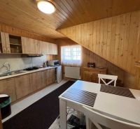A kitchen in a family house with wooden paneling, a white table, and a countertop.