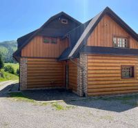 A family house in Veľké Borové with a wood and stone-clad exterior near the forest.
