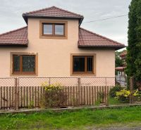 A family house in Ľubela with a red roof and a wooden fence.