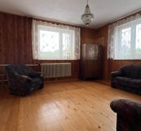 Interior of a family house with a wooden decor floor, sofas, and curtains.