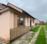 A family house in Ľubela shows a stone driveway, a pink facade, and wooden elements.