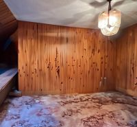 Wooden wall and chandeliers in the attic of a family house with a wooden decor floor.