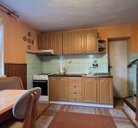 A kitchen with wooden decor, a table, and stairs in a family house.