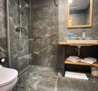 Bathroom in a holiday apartment with dark tiles and a shower corner.