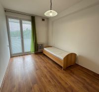 A room in a 2-bedroom apartment with a wood-patterned floor and a bed.