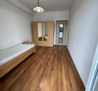 A room in a two-room apartment with a bed, a wardrobe, and a floor with a wooden decor.
