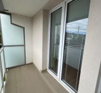 Balcony of a 2-room apartment with a tiled floor, railing, and glass doors.