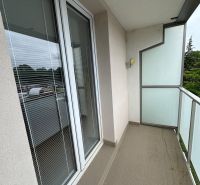 A balcony in a 2-room apartment with glass railings and a tiled floor.