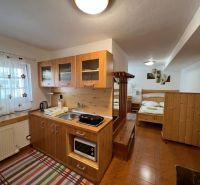 A hotel room with a kitchenette, a bed, and a wooden floor.