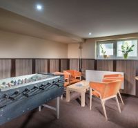 A relaxation room with a foosball table, orange armchairs, and a television in hotels and guesthouses.