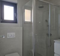 Bathroom with a glass shower enclosure and toilet in a 4-room apartment.