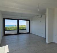 Living room in a four-room apartment with a large window and a view of the sea.