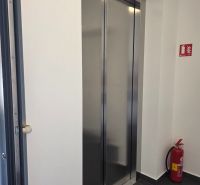 An elevator in a four-room apartment with tiles and a fire extinguisher.