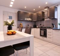 A kitchen in a family house with subtle decorations, fruit, and a white table.