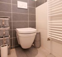 A bathroom with tiles and storage baskets in a family house.