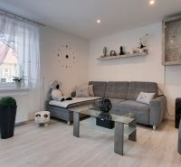 Living room with a sofa and wood-patterned flooring in a family house.
