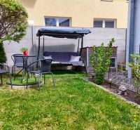 The garden of a family house in Košťany nad Turcom with a swing, chairs, and greenery.