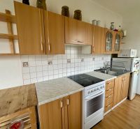 Kitchen in a studio apartment with wood decor flooring, light cabinets, ceramic tiles.