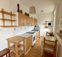 A kitchen in a studio apartment with a wooden decor floor and wooden furniture.