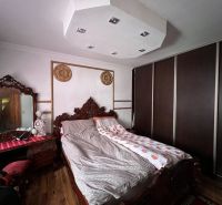 A bedroom with rich wooden furniture, a floor with a wooden decor, and a large built-in wardrobe.