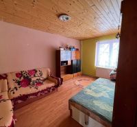 A room in a family house with a wooden decor floor and a floral sofa.