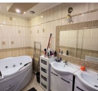 A bathroom with a corner bathtub, two sinks, and a large mirror in a family house.