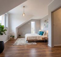 A bedroom in a family house with greenery and a wooden decor floor.