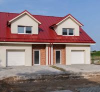 A family house in Andovce with a red roof and a garage, with landscaped terrain in front of the house.