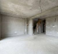 Unfinished interior of a family house with concrete walls and staircase.