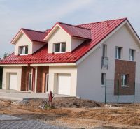 A family house in Andovce with a red roof and white garage doors.