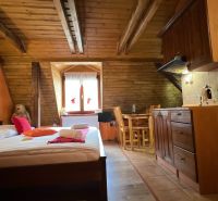 Wooden beams, bed, kitchenette, and table in the attic of the Villa.